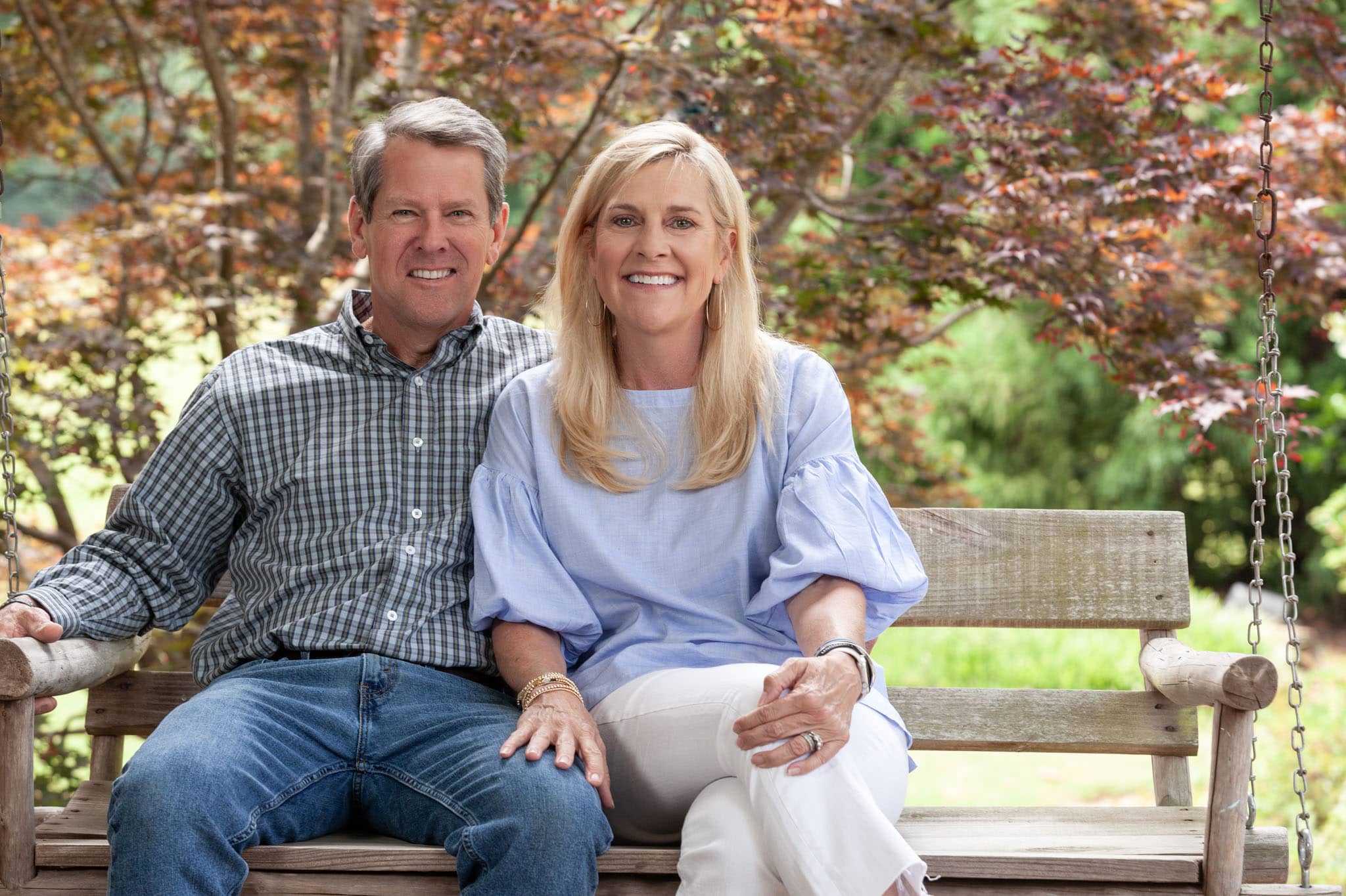 Georgia Governor Brian Kemp and First Lady Marty Kemp sitting next to each other and smiling in a porch swing at their home in Athens, Georgia.