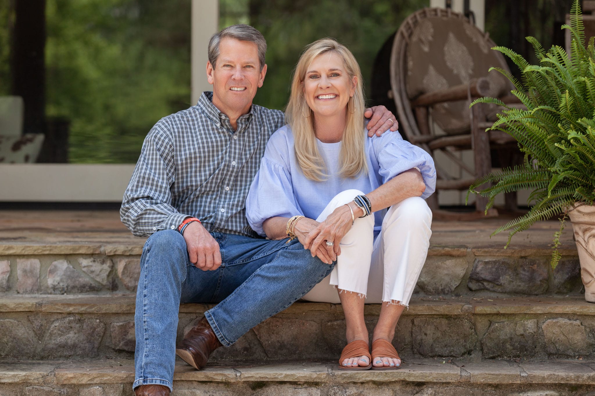 Georgia-Governor-Brian-Kemp-and-First-Lady-Marty-Kemp-sitting-sit-by-side-smiling-on-the-steps-of-their-home-in-Athens-Georgia.