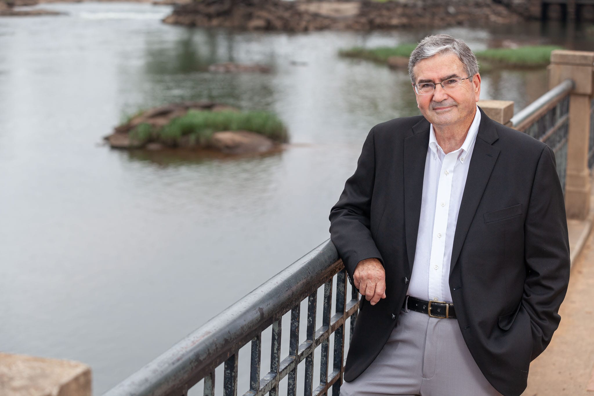 Georgia-Representative-Richard Smith-leaning-against-an-riverwalk-arm-rail-with-the-Chattahoochee-River-in-Columbus-Georgia-in-the-background