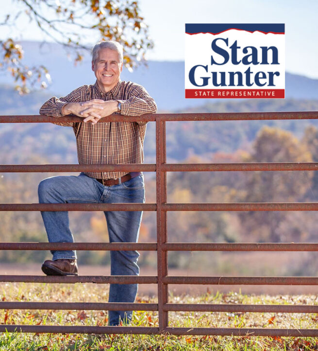 stan-gunter-propped-up-on-farm-fence-while-logo-is-in-top-left-corner-of-picture